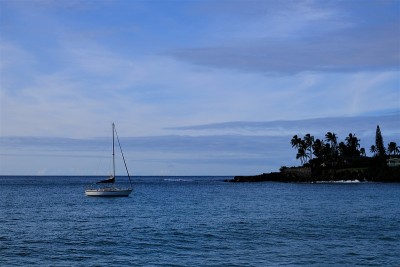 一艘帆船停泊在夏威夷瓦胡岛的威美亚湾，背景是冲浪点
