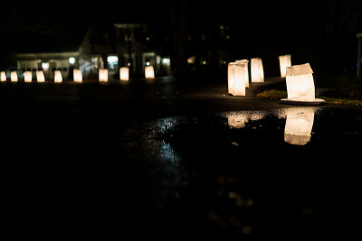 平安夜的烛光火焰特写在水坑里映照在纸袋里，晚上在街道上排列着街道，在节日期间被居民区的房子装饰在盘子
