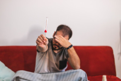 一名年轻男子捧着用于COVID-19自检的棉签，同时捧着自己的头