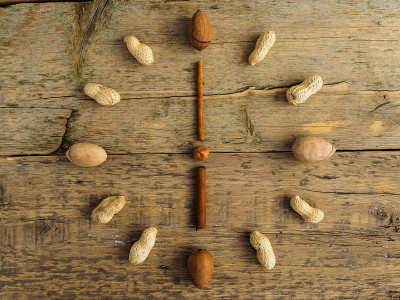 Clock made of different nuts and cinnamon on woode