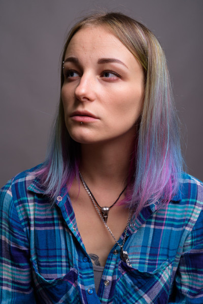 工作室拍摄的年轻美丽的女人与多色头发穿着蓝色格子衬衫对灰色的背景
