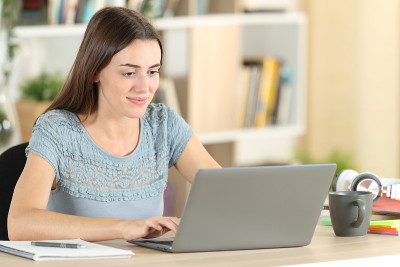 Student writes on laptop e-learning at home