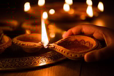 快乐的排灯节-手握或照明或安排排灯节diwali diya或粘土灯在黄铜板，选择性焦点