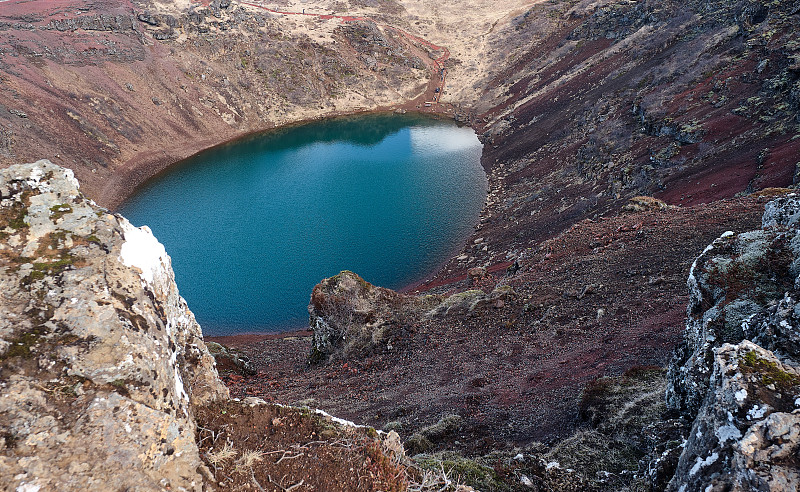 清澈的深蓝色湖泊，反映了被红色火山岩包围的冰岛克里德火山口底部周围的地下水位