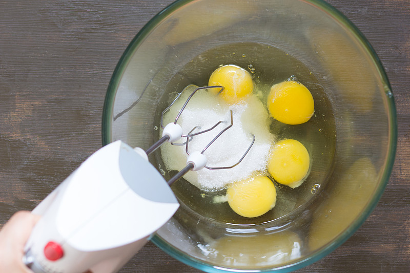 Woman hand holding mixer in glass bowl with sugar 