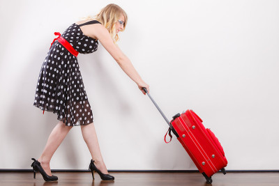女人拉着沉重的红色旅行袋