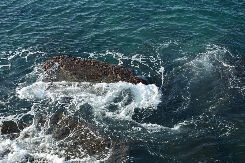 海浪拍打着岩石，溅起白色的泡沫