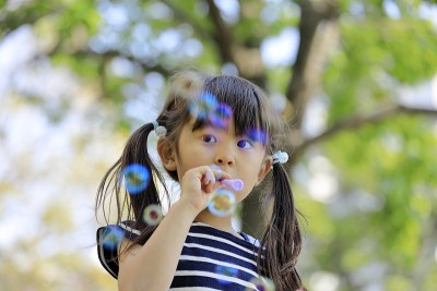 日本女孩在绿色中玩泡泡(5岁)