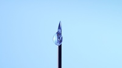 医用疫苗从注射器针头滴下。新型冠状病毒(COVID-19)疫苗实验室开发研究概念。临床前评估和临床试