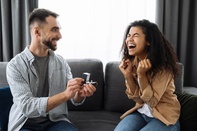 求婚。给心爱的女人一个惊喜。一个男人把订婚戒指送给他心爱的非裔美国女孩，她很高兴地接受了。幸福的情侣