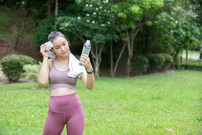 女子在公园锻炼后拿着一瓶水休息。