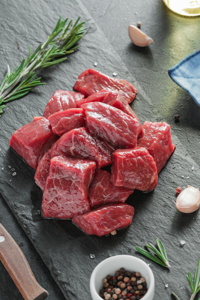特写切碎的生牛肉与新鲜迷迭香和香料在黑色的桌子上。
