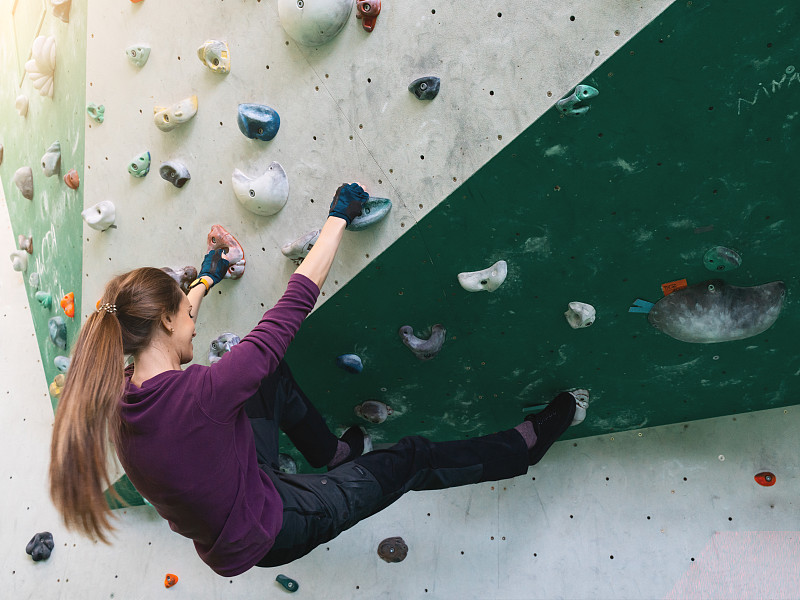 A woman climbing in boulder gym in the wall.