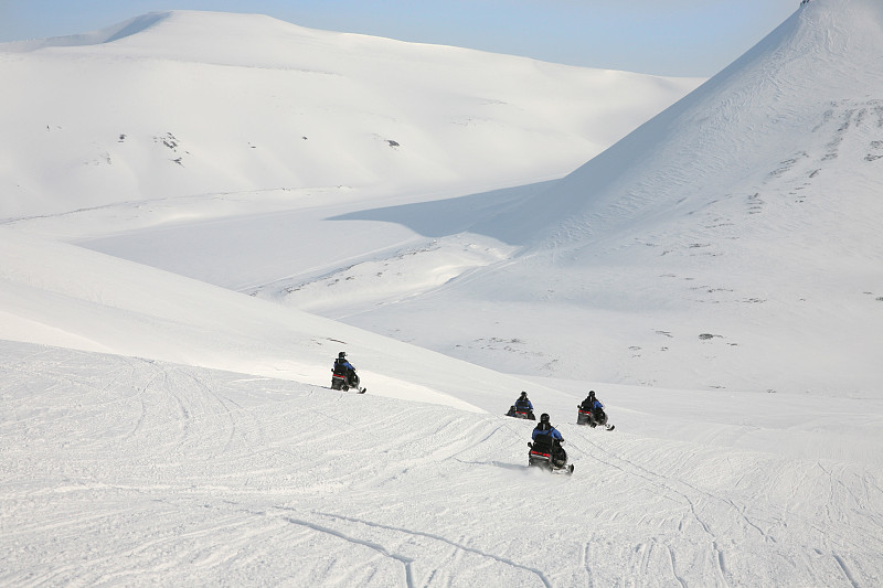 在挪威斯瓦尔巴特群岛的北极圈山脉上乘坐雪地摩托旅行