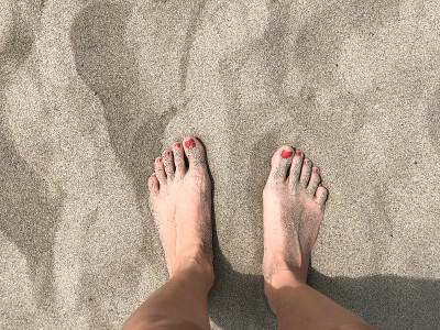 两个女人的脚在沙地上特写。假期的概念