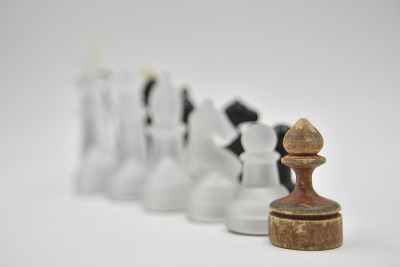 玻璃象棋人物后面的木制庞塞在白色的背景