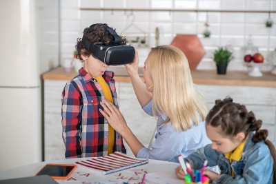 金发女孩戴上vr眼镜卷男孩，黑发女孩坐在圆桌旁写作