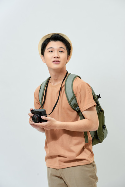快乐的男人戴着尖顶帽，脖子上挂着照相机，背景是白色