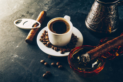 一杯咖啡，咖啡豆，烟灰缸和雪茄在黑暗的背景
