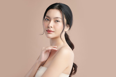 美丽的年轻亚洲女人与干净的新鲜皮肤上米色的背景，面部护理，面部治疗，美容和水疗中心，亚洲妇女肖像。