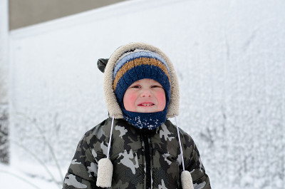小男孩在街上玩雪。