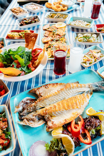 烤鱼、沙拉和蔬菜。海鲜，烤肉，meze, raki, ouzo，开胃菜和沙拉在希腊或土耳其鱼餐厅的桌
