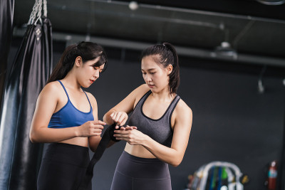 年轻的亚洲女子体育训练拳击手准备带腕上教练教练，拳击练习运动的战斗或与一个伙伴在健身馆锻炼健康的生活