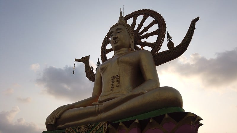 日落时苏梅岛的大佛寺。佛寺耶艾寺。金色的佛像。云。佛教的地方。东方宗教。灵性。