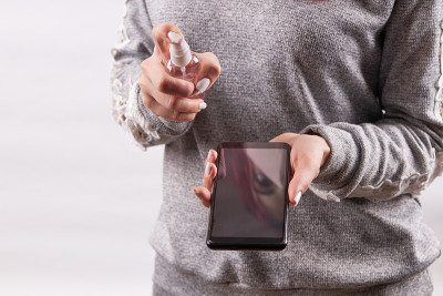 白人女性使用酒精消毒剂清洁手机或智能手机。covid-19保护概念。