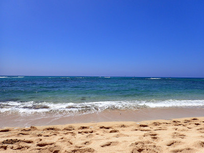 柔和的波浪拍打着海滩，海平线上的小船