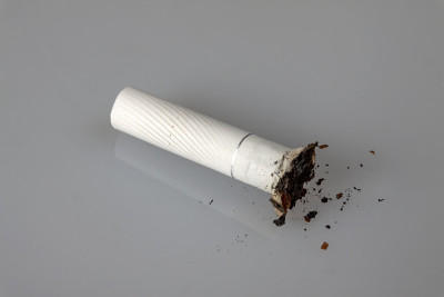健康的生活方式的概念。一个小烟头躺在一个轻的表面，一排一点灰。