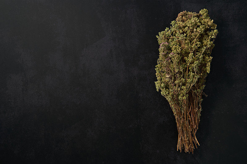 一束牛至在黑暗的背景和空的表面。