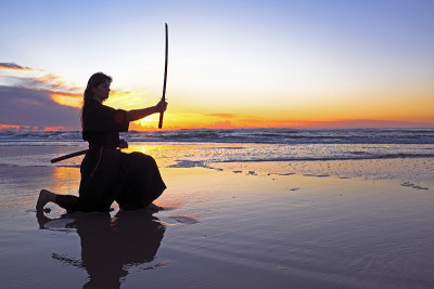 年轻的武士妇女与日本刀(武士刀)在日落上