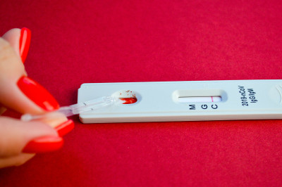 在红色背景上进行冠状病毒检测。一个修了红色指甲的女孩做了血液测试。IgG、IgM抗体测定，敏感分析