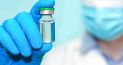 戴蓝手套的医生拿着一个装有疫苗的瓶子。医学、保健和科学的概念