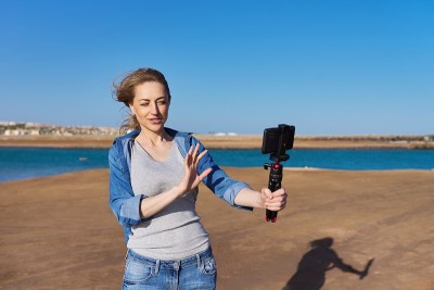 成熟的女人用智能手机录制视频，制作流媒体