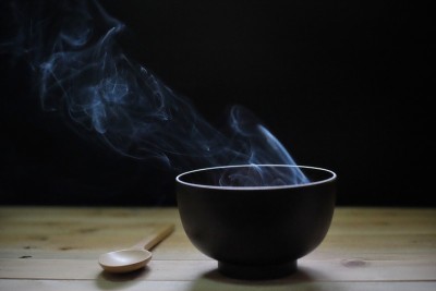 木桌黑色背景，热气腾腾的汤碗