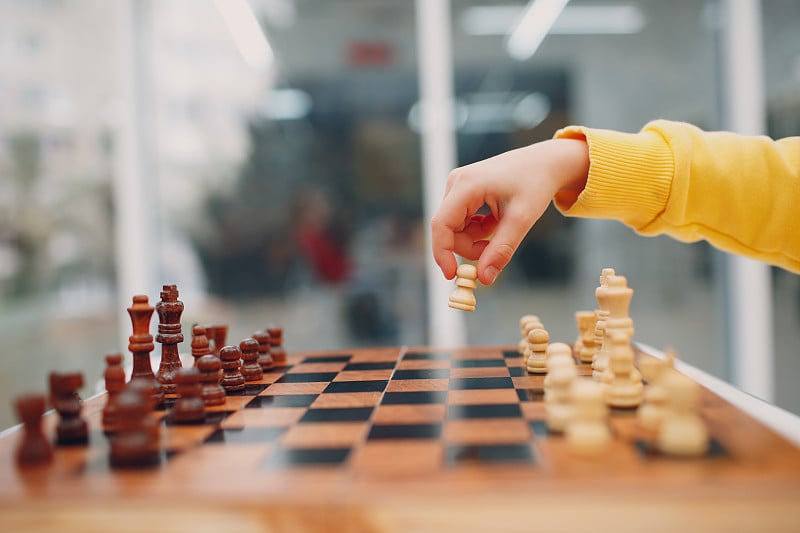 在幼儿园或小学下棋的小孩。手握棋子特写