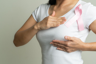 粉红色的徽章丝带在妇女的胸部支持乳腺癌事业。乳腺癌意识概念