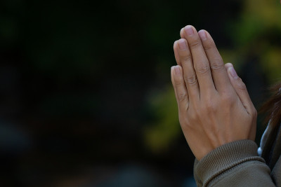 在黑暗的背景上，用信仰宗教和信仰上帝的双手祈祷。支付的尊重。双手合十或Namaskar手势。