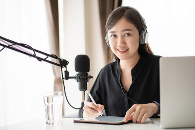 一个亚洲年轻女子在网上播客站做播客。