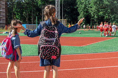 小学生们在学校体育场观看他们如何踢足球。