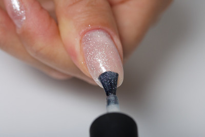 A woman gives herself a manicure. Apply new nail P