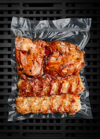 真空包装的烤肉，深色背景。一套不同类型的肉。可以吃了。