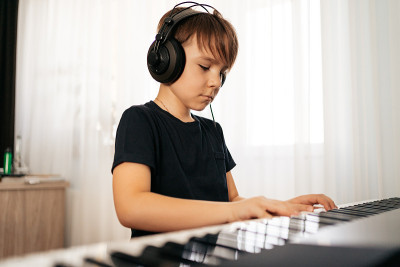 School boy playing synthesizer at home