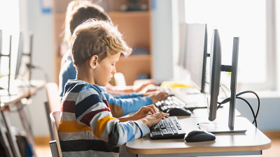 小学计算机科学课堂:可爱的小男孩使用个人电脑，学习编程语言进行软件编码。小学生接受现代教育。侧面肖像
