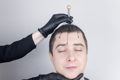 一个男人在沙龙里用毛细管按摩器做头部按摩。客户的脸上流露出放松和喜悦。抗压力按摩的概念和由按摩师提供