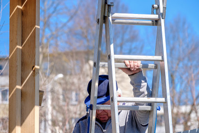 白发苍苍的资深建筑工人迎着蓝天走下楼梯。建造木质乡村房屋的过程。
