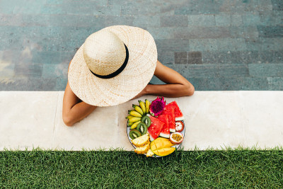 Girl relaxing and eating fruit plate by the hotel 