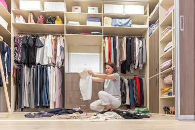 年轻女子把衣服扔进衣橱。衣柜和更衣室乱七八糟